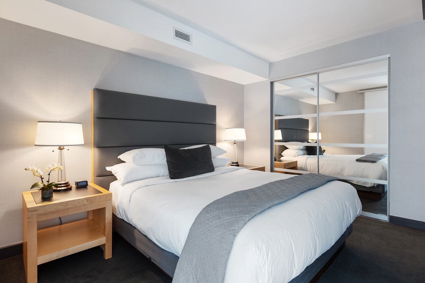 A minimalist bedroom with a mirrored wardrobe